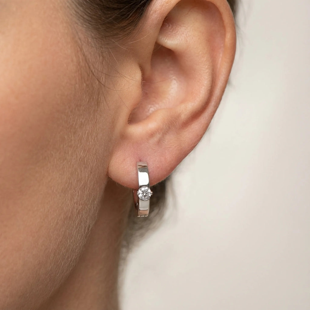 Solitaire Cubic Zirconia huggie earring close on the lobe, side view — 925 sterling silver clicker hoop, rhodium finish