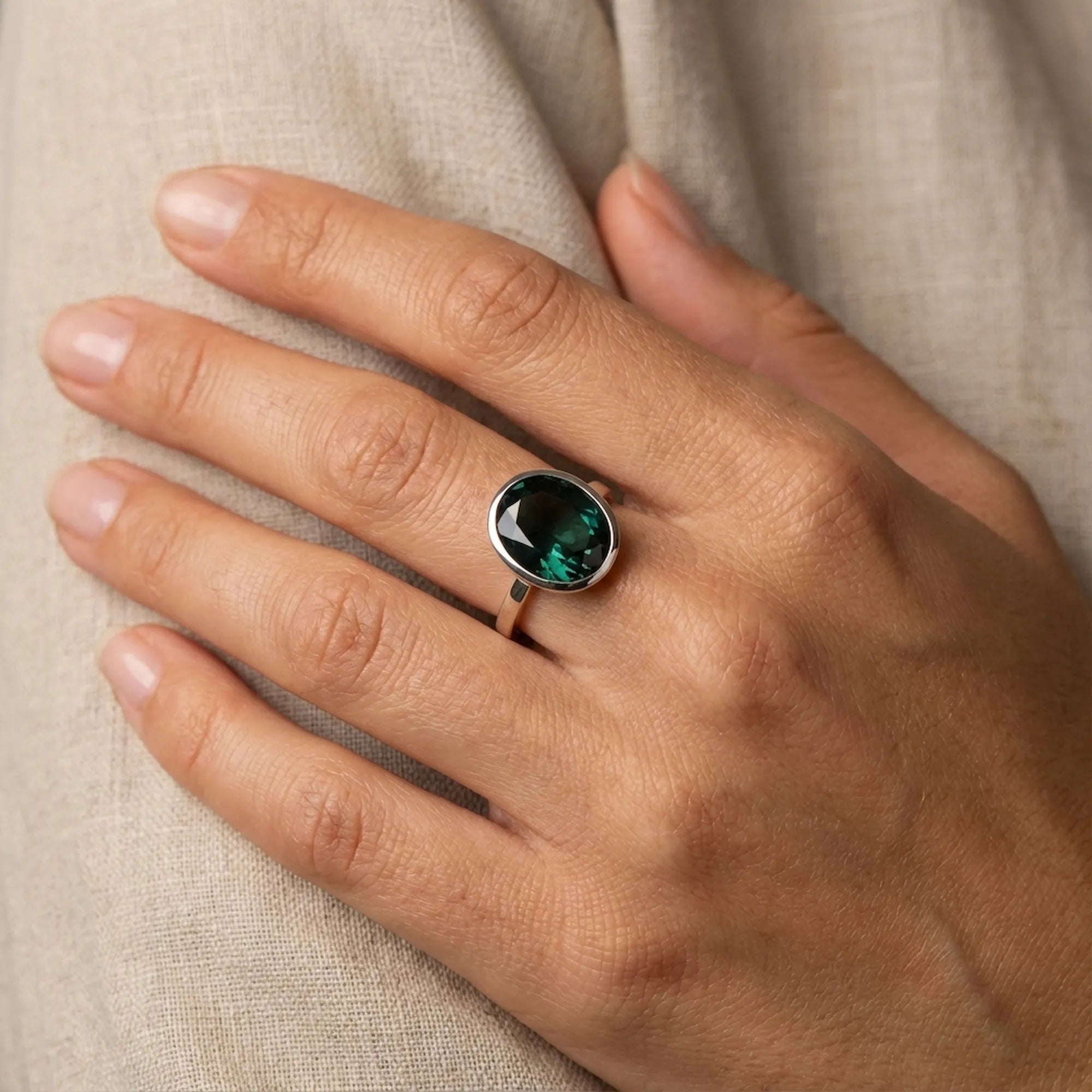 A woman models the 16x12mm oval London Blue Topaz ring on her finger, showing the size and scale of the 925 sterling silver jewelry.