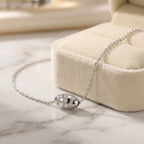 Stardust bead necklace on marble surface beside cream velvet gift box, pavé CZ detail on silver barrel visible