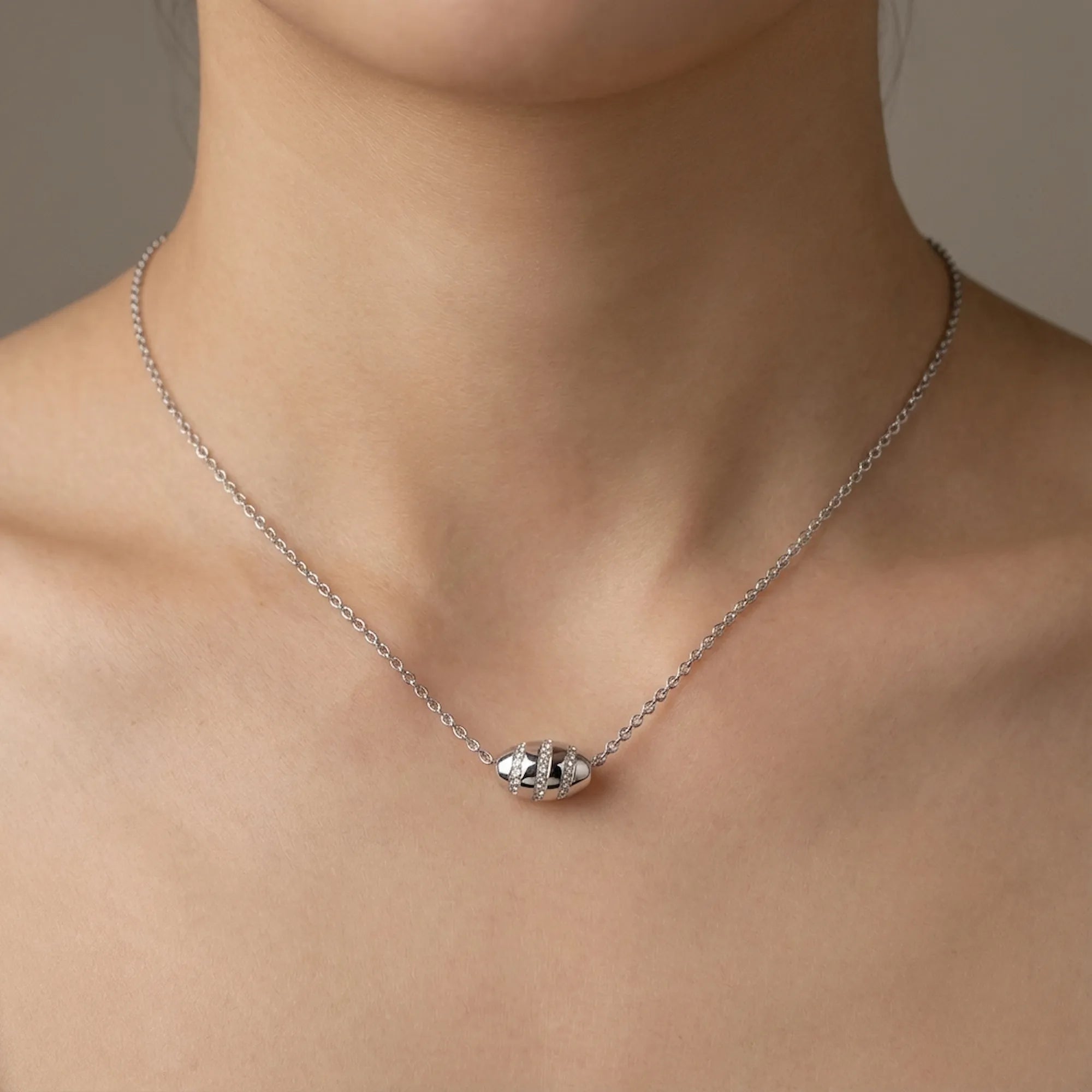 Woman wearing Stardust silver bead necklace at collarbone, micro-pavé CZ bands catching light on neutral background