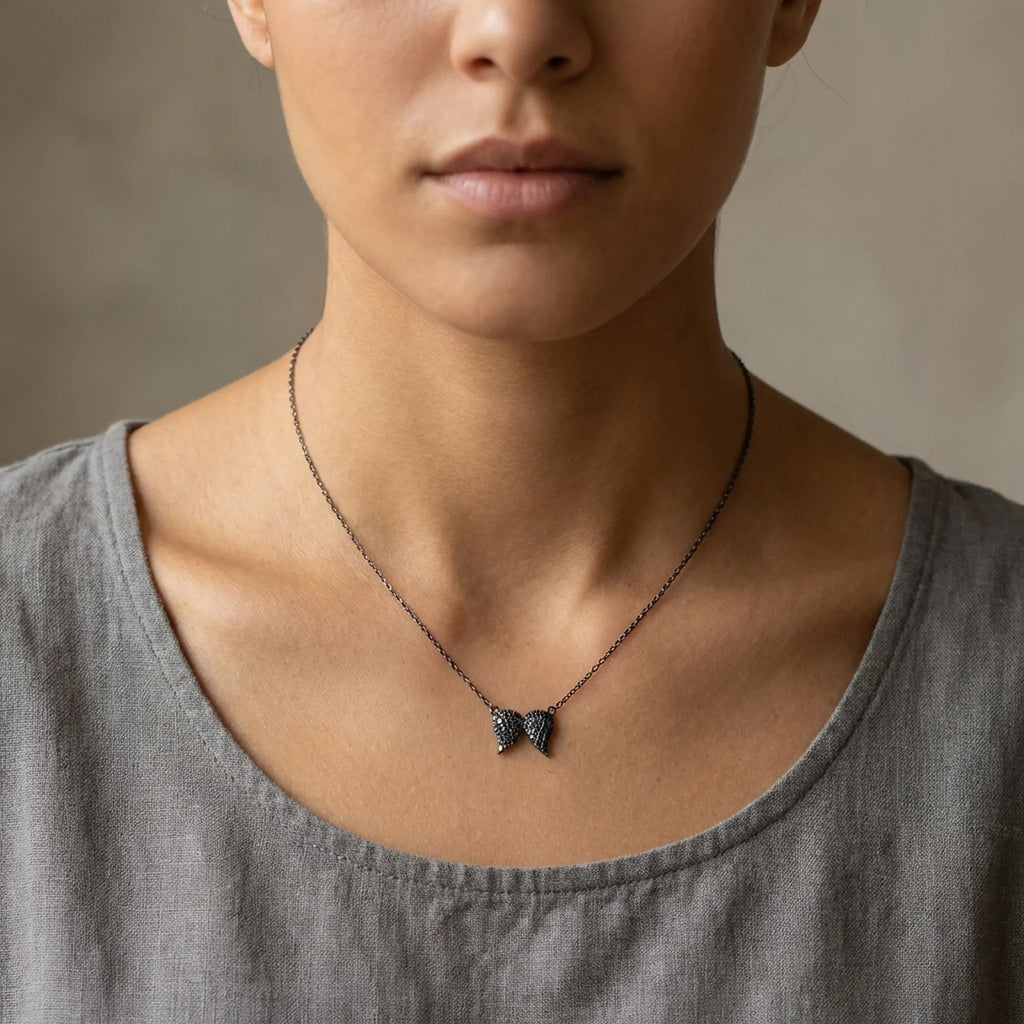 A female model wearing the sterling silver black angel wing necklace demonstrating the true 40cm chain length and pendant fit.
