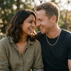 couple model outdoors Male and female wearing a bright silver rope-style chain necklace with olive shirt a dblack T-shirt.