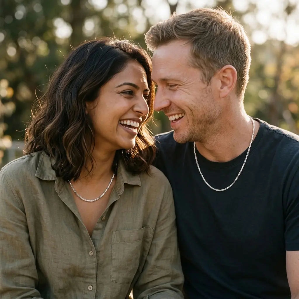couple model outdoors Male and female wearing a bright silver rope-style chain necklace with olive shirt a dblack T-shirt.