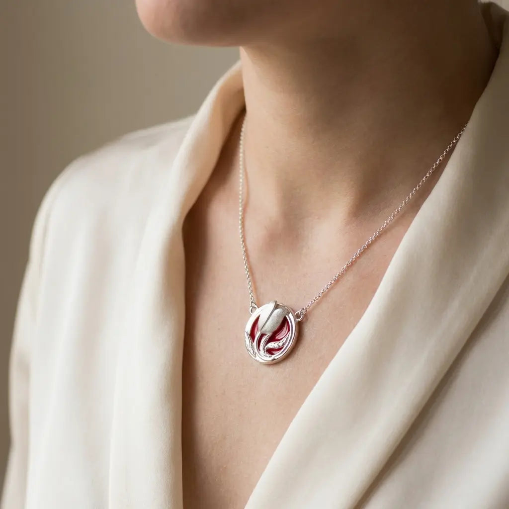 A model wearing the silver red tulip necklace against a silk cream blouse, demonstrating the pendant's size and scale.