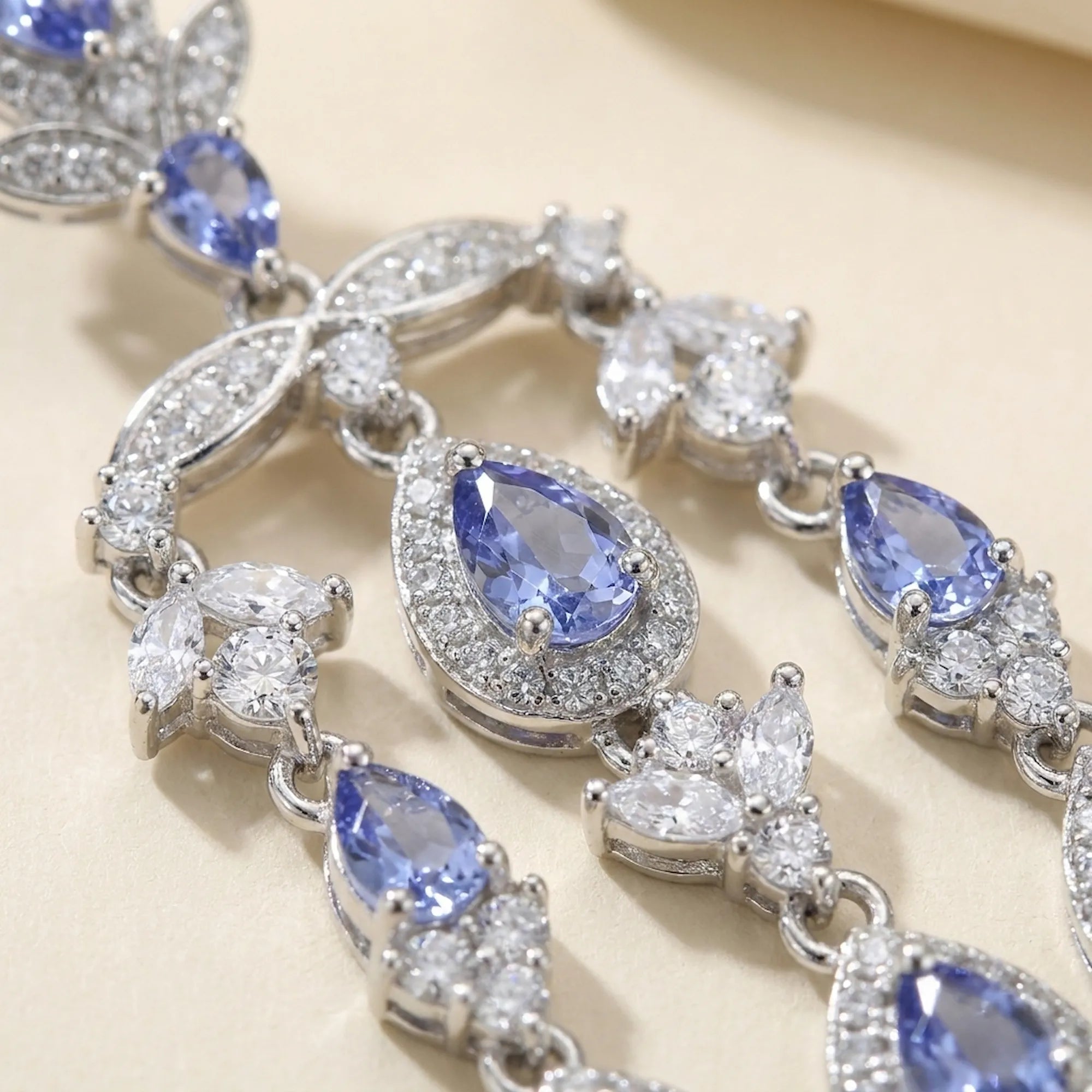 Close-up of pear-cut natural tanzanite and cubic zirconia in a rhodium silver chandelier earring, Luna Dura.