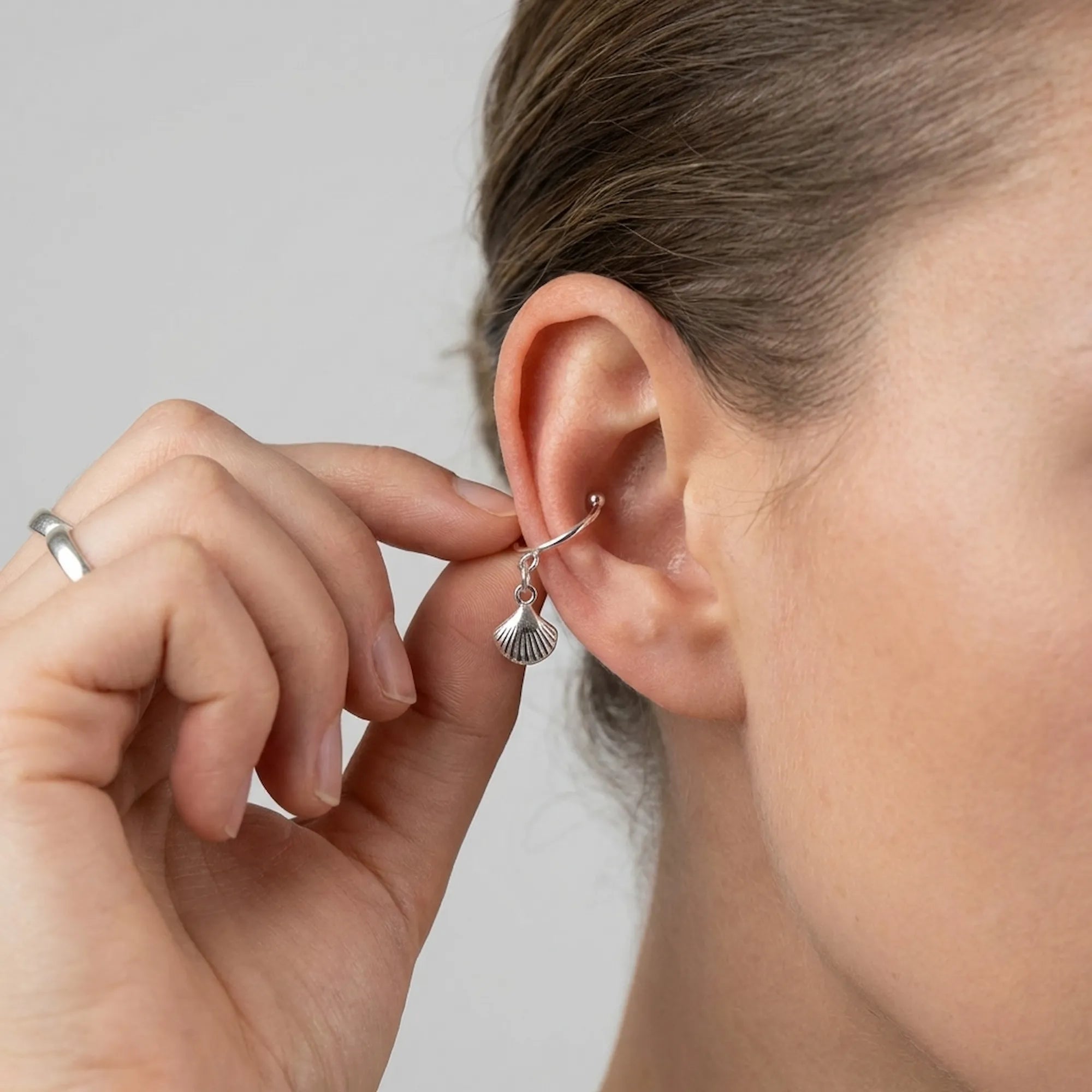 Demonstration of a person easily sliding the tarnish free ear cuff onto their ear cartilage, highlighting the no piercing requirement.