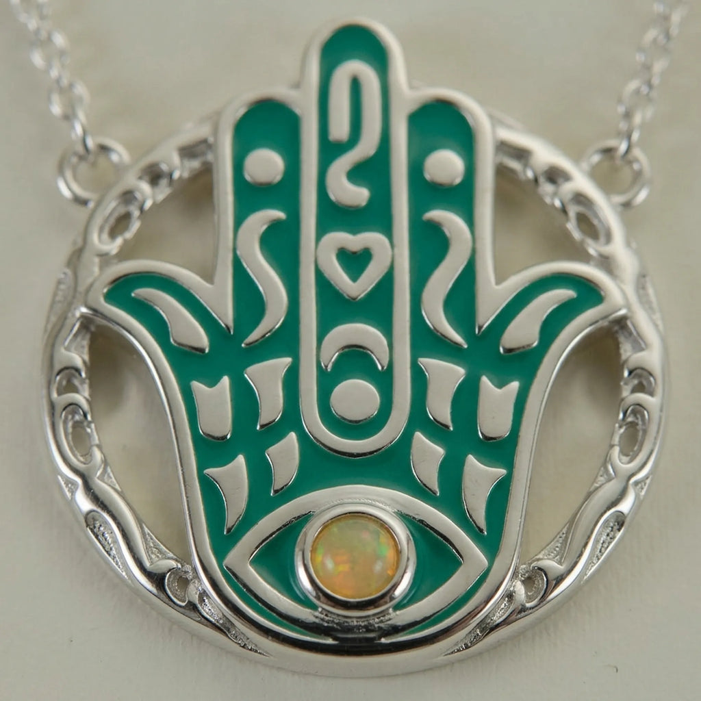 Close-up of a natural yellow opal bezel-set in a teal enamel Hamsa pendant showing its play-of-colour, 925 silver, Luna Dura.