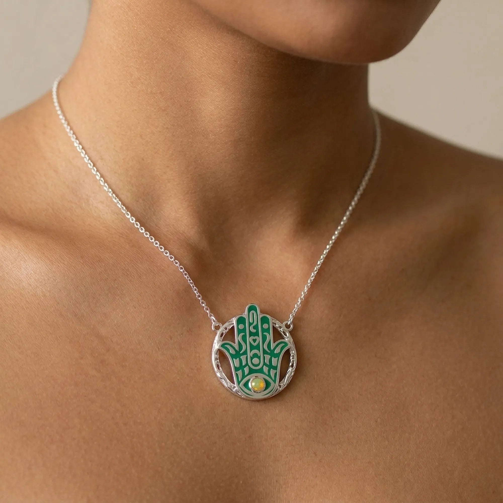 Woman wearing a teal enamel Hamsa pendant necklace with a yellow opal in 925 silver, Luna Dura Dubai.