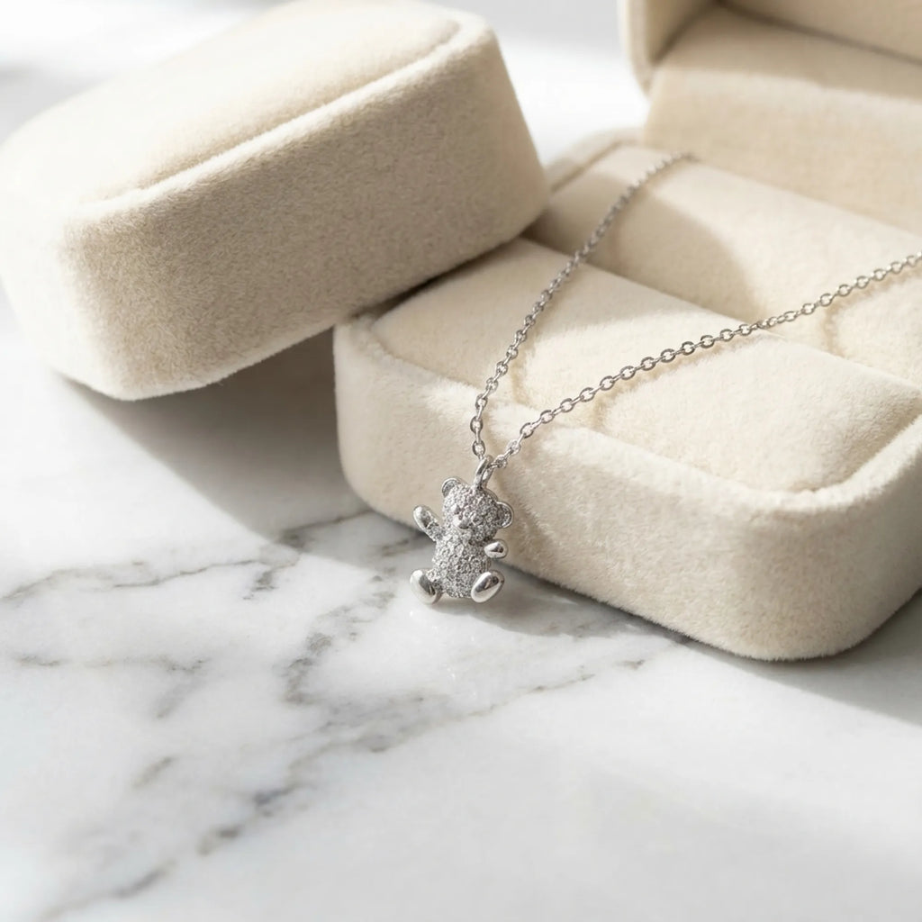 Teddy bear pavé necklace beside open cream velvet jewelry box on marble — gift necklace Dubai UAE rhodium 925 silver