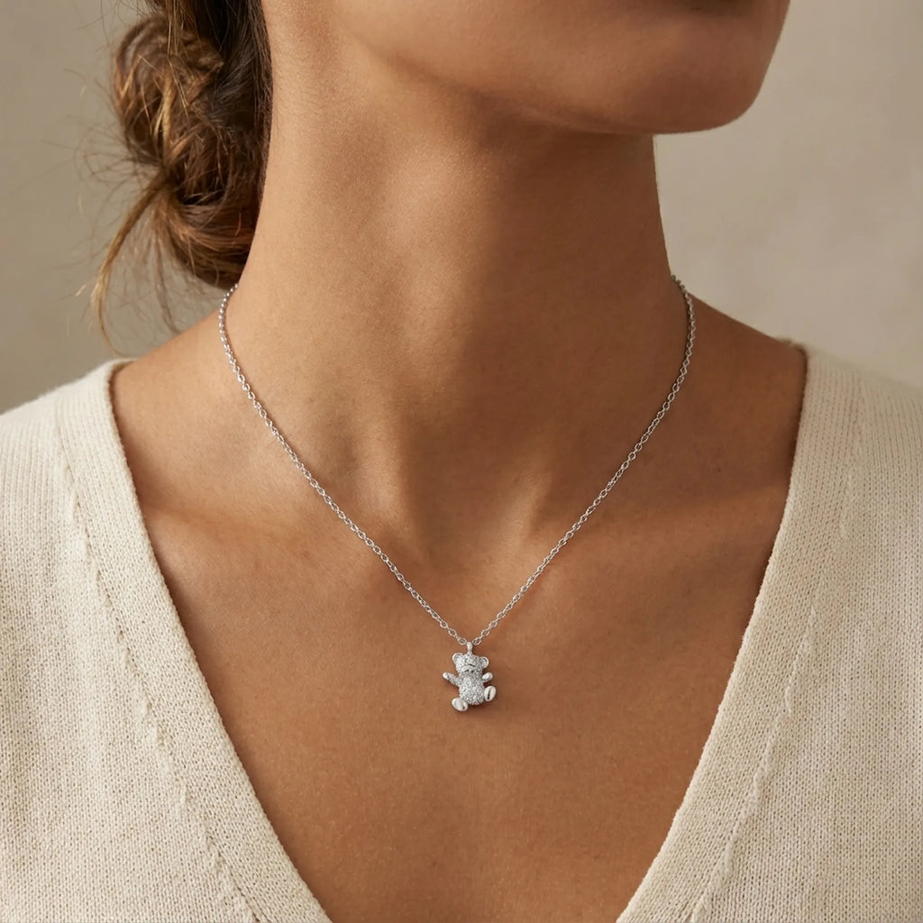 Teddy bear pavé necklace worn at collarbone on model in cream knit top — fully set cubic zirconia bear pendant rhodium 925 silver Dubai