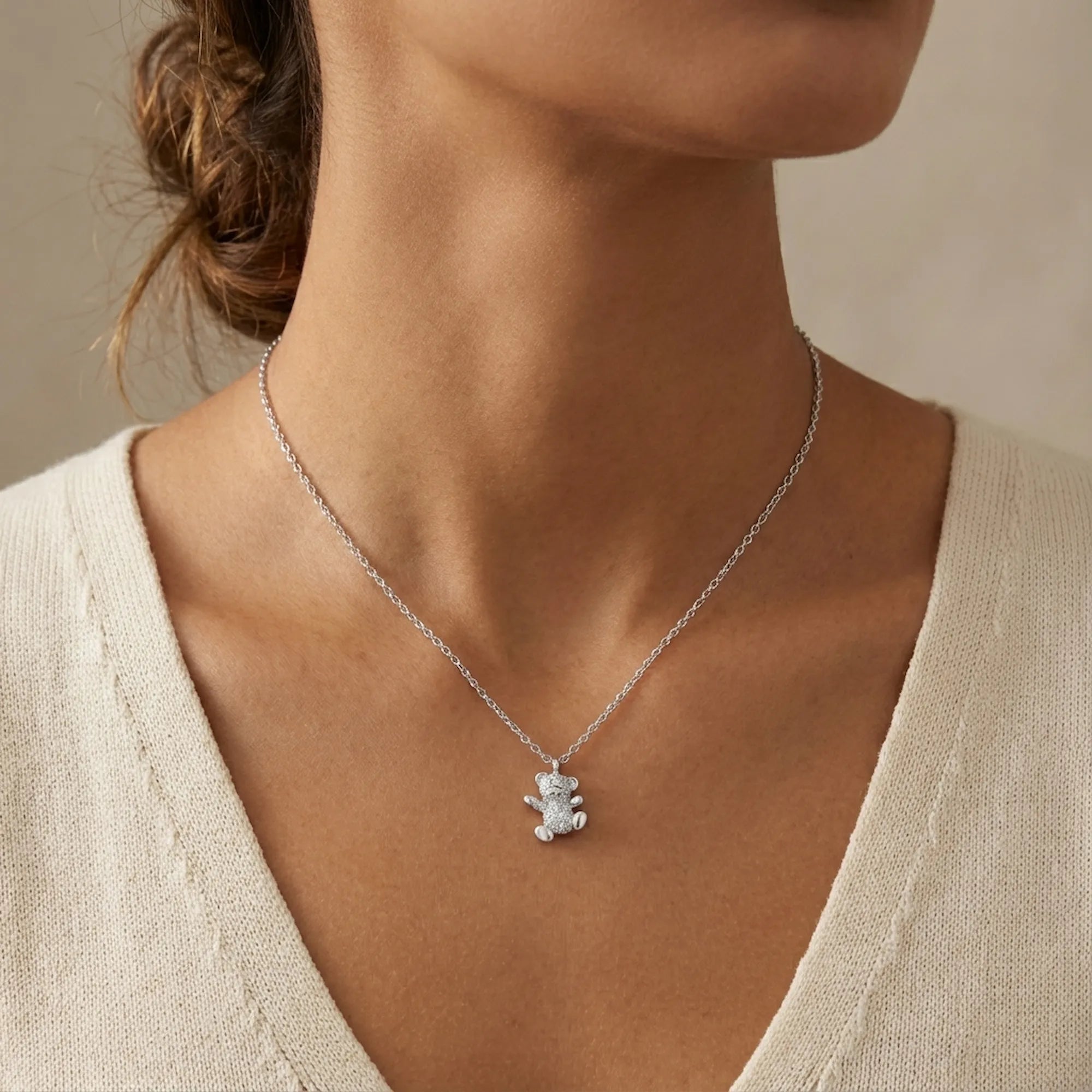 Teddy bear pavé necklace worn at collarbone on model in cream knit top — fully set cubic zirconia bear pendant rhodium 925 silver Dubai
