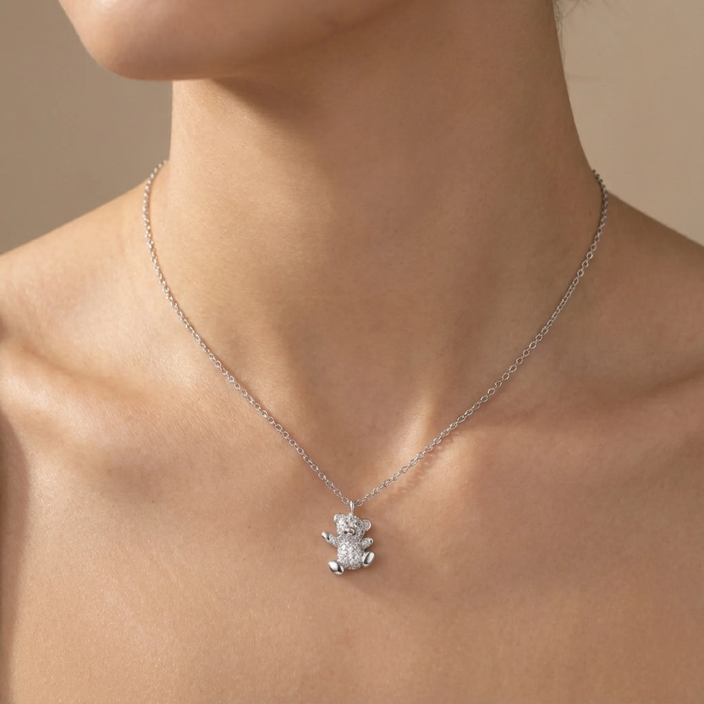 Pavé teddy bear pendant at bare collarbone — rhodium silver cable chain and fully stone-set bear form 925 sterling silver