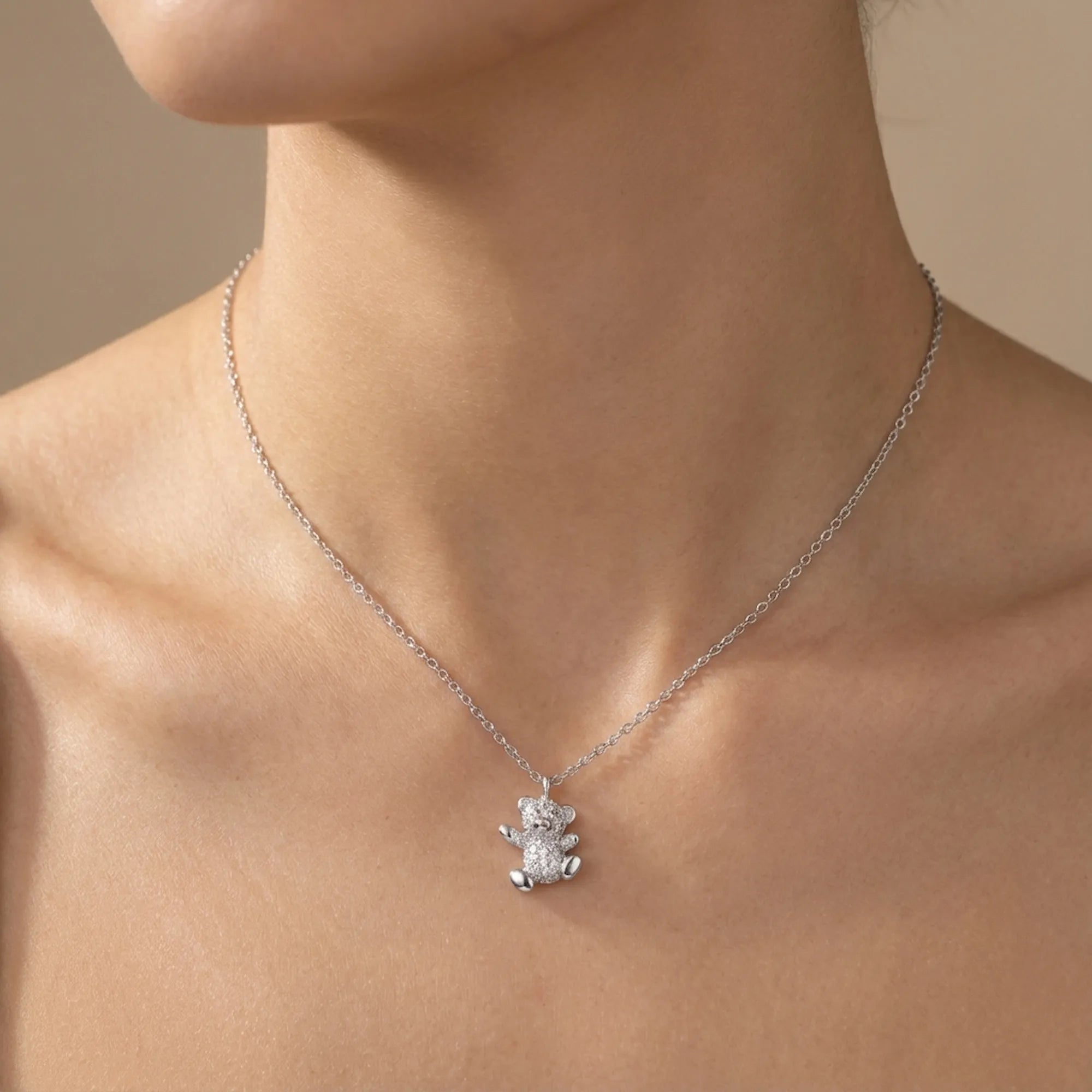 Pavé teddy bear pendant at bare collarbone — rhodium silver cable chain and fully stone-set bear form 925 sterling silver
