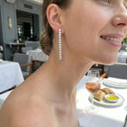 Model wearing CZ tennis drop earrings at La Petite Maison DIFC Dubai — 40mm stone line against neck at formal dinner setting
