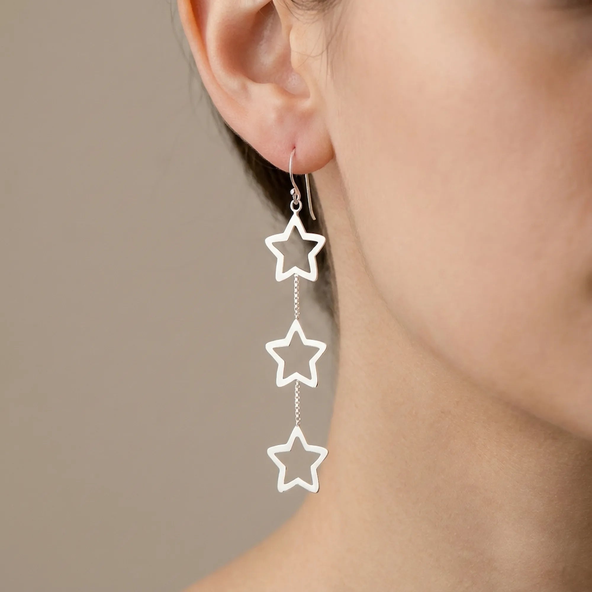 925 sterling silver triple star drop earrings worn on model ear with three open star frames on a box chain