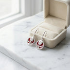 Red enamel tulip drop earrings in 925 sterling silver alongside open cream velvet jewelry box on marble