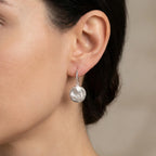 Close-up of silver tulip drop earring on ear showing sculpted bud and circular disc detail