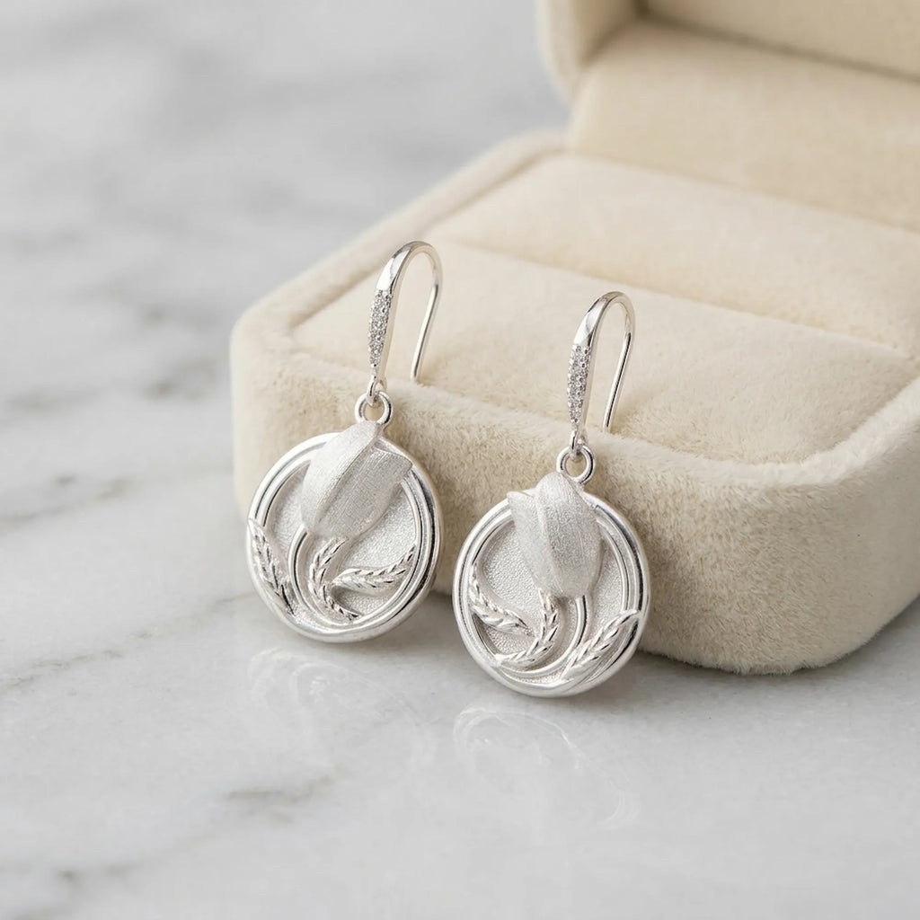 Pair of silver 925 sterling silver tulip drop earrings in open cream velvet jewelry box on marble