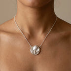 Close-up tulip medallion necklace on bare collarbone — satin silver bud in polished rim, 925 sterling silver