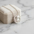 Tulip medallion necklace against cream velvet box on marble — 925 silver satin pendant, gifting flat lay