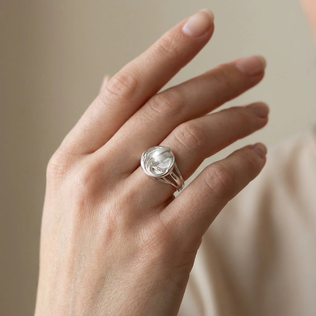 Satin silver tulip medallion ring worn on hand showing three-track bypass band detail