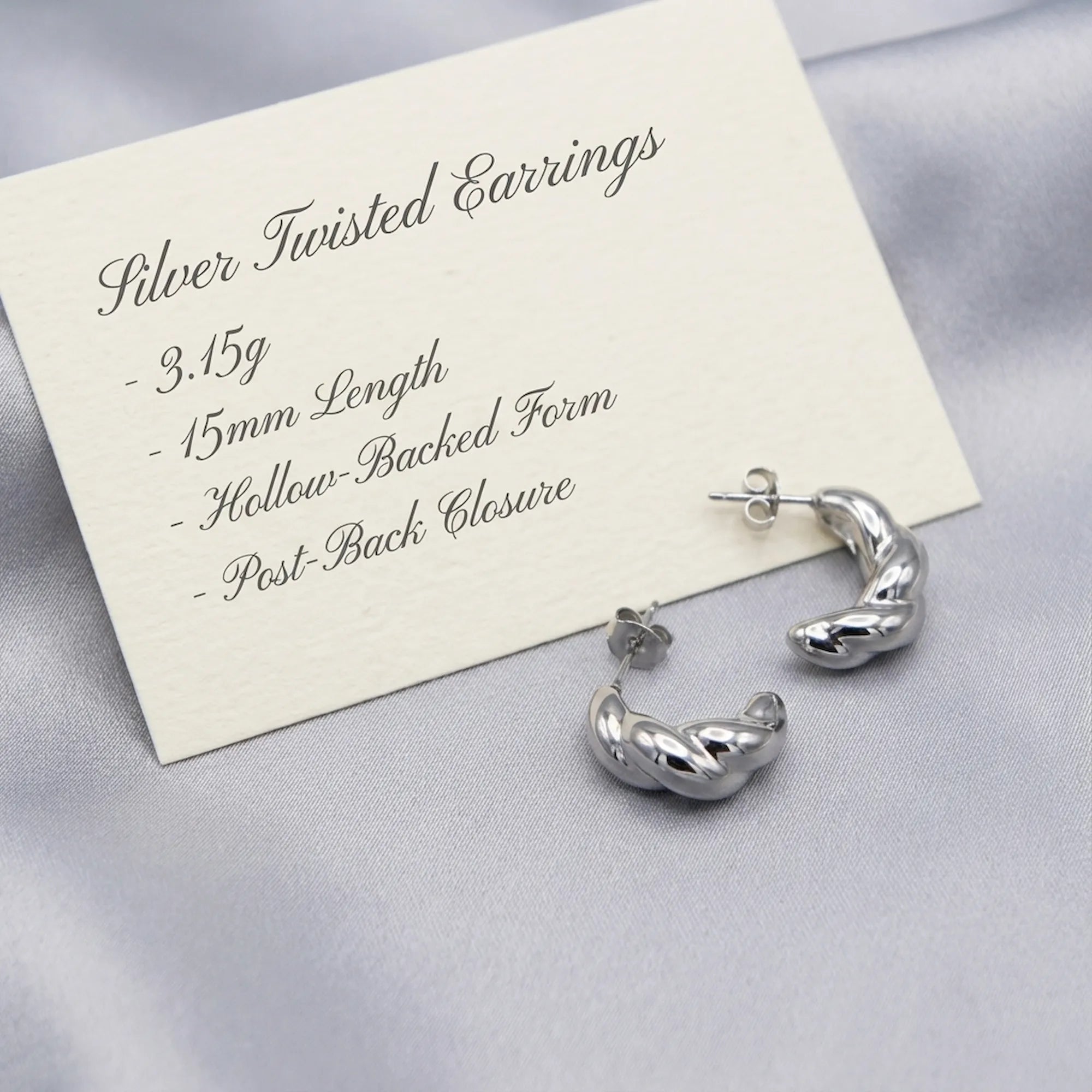 Silver twisted hoop earring spec card showing 3.15g weight, 15mm length, hollow-backed form and post-back closure
