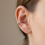 Close-up of twisted rope silver ear cuff worn on cartilage conch position showing oxidized groove detail and ball end Dubai.