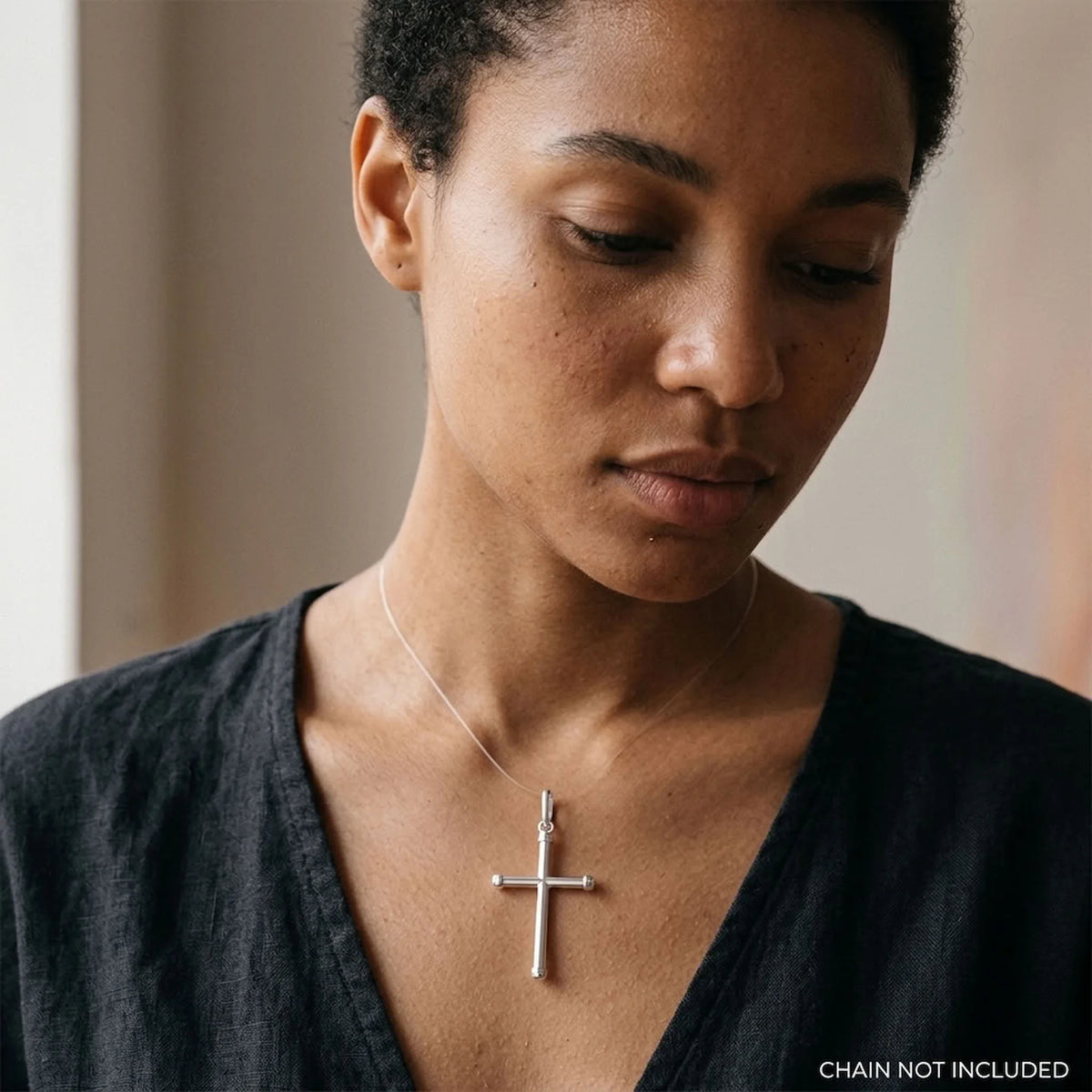 Woman wearing a polished 925 sterling silver tubular cross pendant, chain not included.