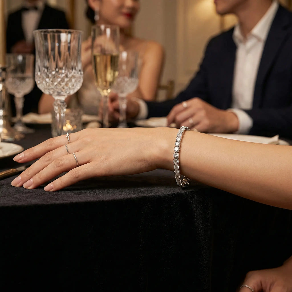 Elegant lifestyle view of a white CZ tennis bracelet worn at a formal dinner setting with champagne glasses and fine dining decor