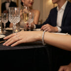 Elegant lifestyle view of a white CZ tennis bracelet worn at a formal dinner setting with champagne glasses and fine dining decor
