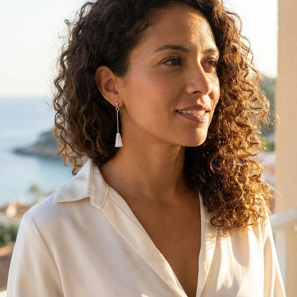 Woman wearing a white stone silver drop earring by the sea, 925 sterling silver plumb-line drop, Dubai