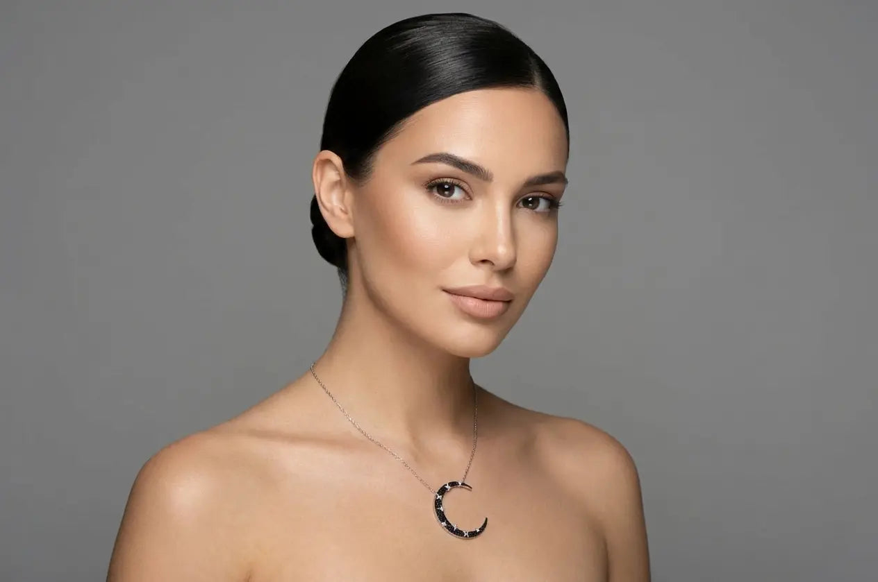 A studio portrait of a woman in Dubai wearing a Luna Dura silver necklace with a large crescent moon pendant encrusted with black stones